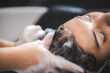 © chokniti - young beautiful woman client getting hair treatment in beauty salon with professional female stylist hairdresser, using shampoo and water on person head to clean and coiffure hair fashion service