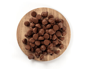 Poster - Top view of Chocolate chips on a circular wood plate on white background