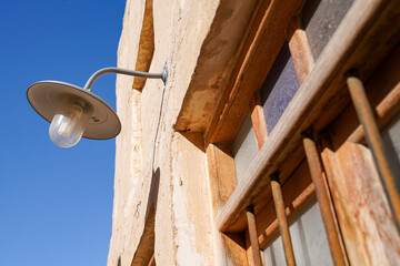 Sticker - Low angle of a Vintage Industrial Stable Lamp Outdoor on the wall against a blue sky in Doha, Qatar