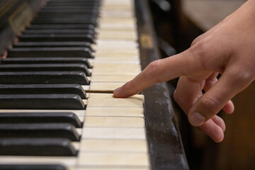 Close-up shot of a finger pressing an old vintage piano key