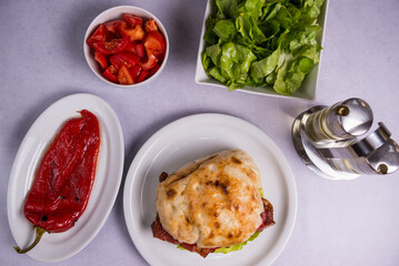 Sticker - Top view of a burger with homemade bread and bacon with some tomatoes, lettuce and pepper near it