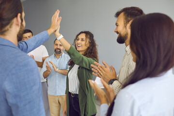 Wall Mural - Business team celebrates its success. Group of excited business people giving each other ahigh five after productive corporate meeting in office. Concept of success, teamwork, support and positivity.