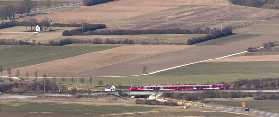 Poster - Long exposure shot of a red and blue train on the railway in an agricultural field