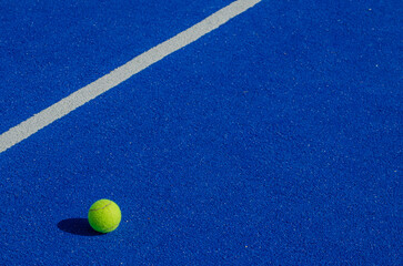 Wall Mural - Isolated ball on a blue paddle tennis court, racket sports concept