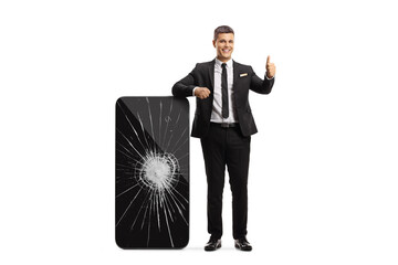 Wall Mural - Professional man in leaning on a big smartphone with a broken screen and gesturing thumbs up