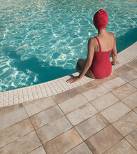 Woman Relaxing In The Pool In Red Swim Suit And Bathing Cap In Summer