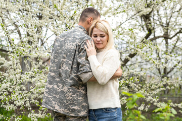 Wall Mural - Soldier is hugging a woman outdoor. Reunion of a couple in the evening park