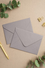 Business Concept. Top View Vertical Photo Of Two Grey Envelopes Gold Pen Binder Clips And Eucalyptus On Beige Background