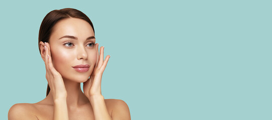 Wall Mural - Moisturizing and facial treatment. Beauty portrait of beautiful model with perfect skin touching her face. Web banner with cope space