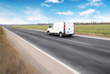 Fototapeta Sport - White van on a countryside road in motion against a sky with clouds