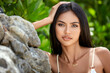 Beautiful asian girl in a white bikini posing on a beach with rocks