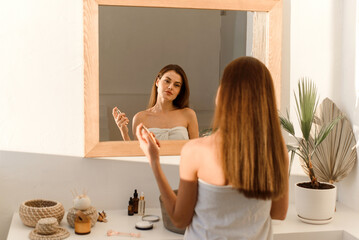 Sticker - A lovely young woman uses a moisturizing mist spray for glowing skin. Moisturizing, home care and spa concept.