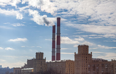 Poster - CHP in the city. Smoke rises into the sky from the heat pipes of the power plant. Pipe of combined heat and power plant CHP or cogeneration against background of multi-storey residential buildings