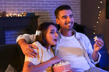 Sticker - Happy young couple with popcorn watching movie at home in evening