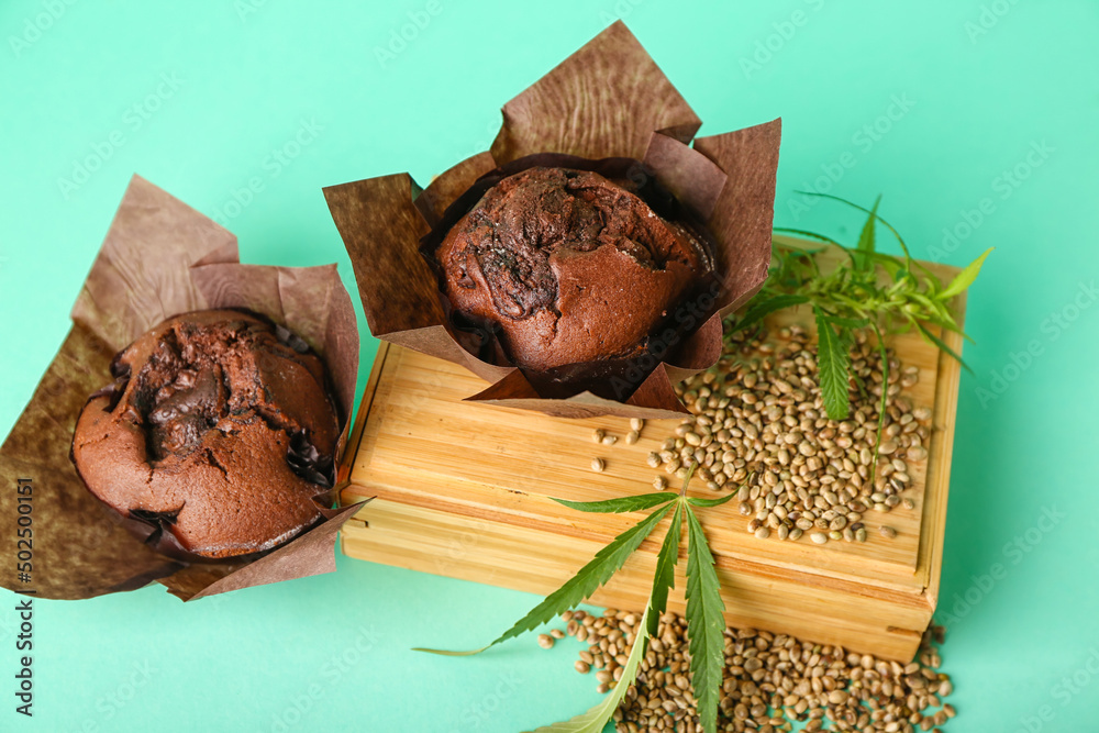 Composition with chocolate hemp muffins, seeds and leaves on color background, closeup