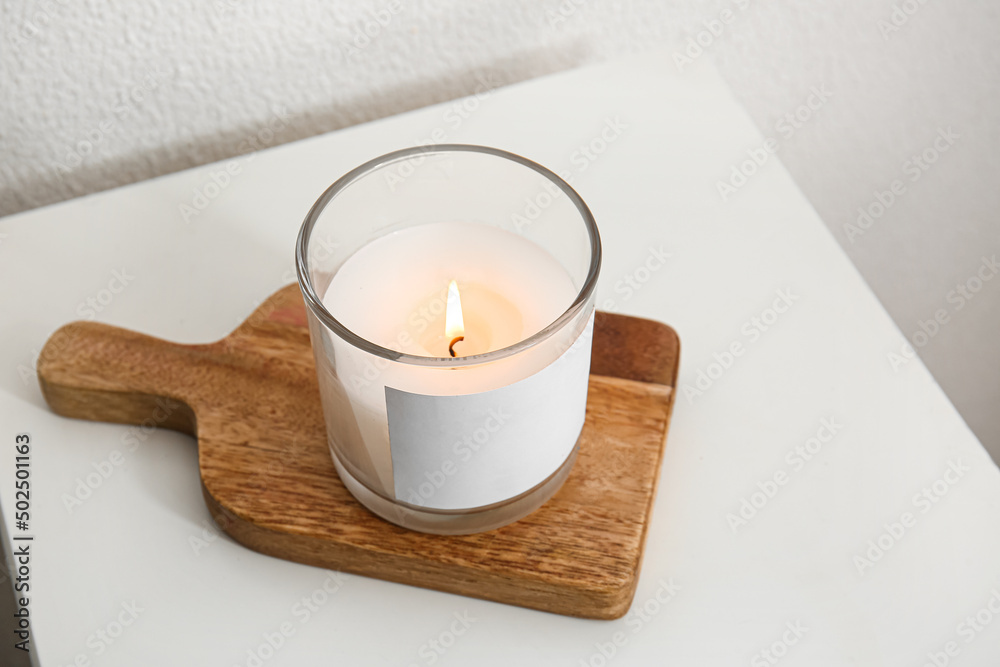Holder with burning candle on table, closeup