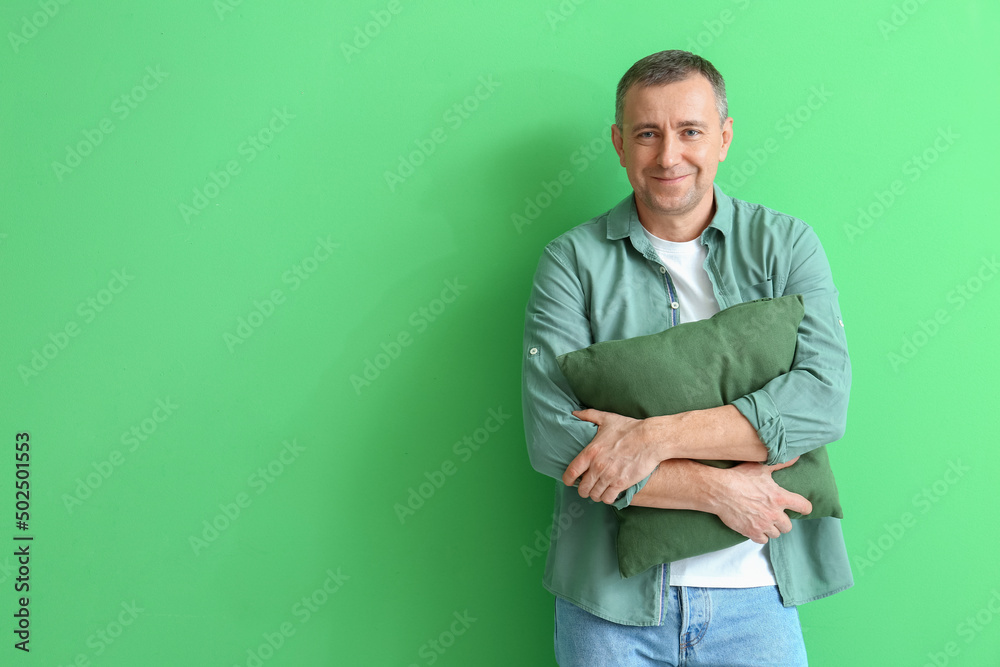 Mature man hugging pillow on green background