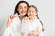© Pixel-Shot - Little girl with her mother brushing teeth on light background