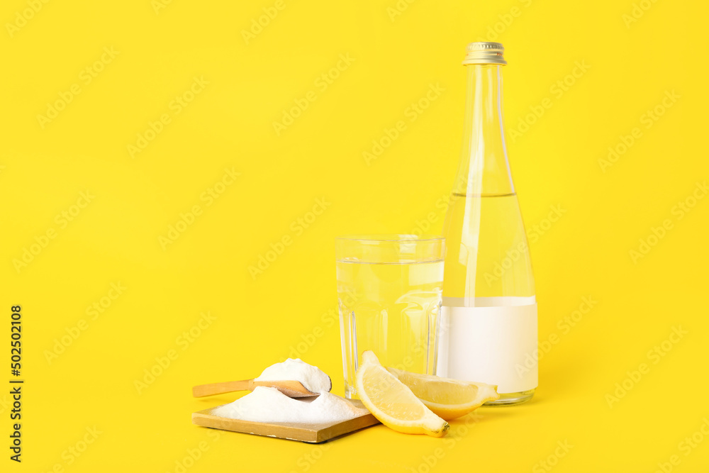 Composition with baking soda, ripe lemon and water on yellow background