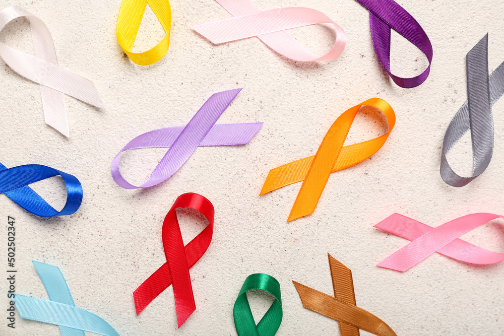 Awareness ribbons scattered on light background, closeup. World Cancer Day