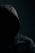 Man in dark camouflage hoodie with covered face dark background, hacker bandit and attacker.