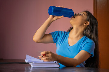 Wall Mural - Young Indian girl drinking water while studying, Stay hydrated