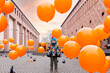 © Anna - Boy in autumn staying in the street surrounded with orange balloon. Travelling with children in Europe, street art, city autumn festival, Halloween.