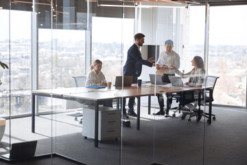 Wall Mural - people standing near table, team of young businessmen working and communicating together in office.