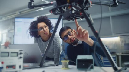 Poster - Black Male Engineer Put at Laptop Screen and Talk while Brainstorming with his Female Colleague about Drone Design. Innovative Technologies in Unmanned Aerial Vehicle Design Concept. Slow Motion
