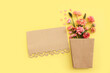canvas print picture Top view image of pink flowers composition and empty note over yellow pastel background
