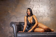 © Igor Link - Sexy young woman with long legs sitting on a dark brown leather sofa