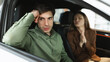© Prostock-studio - Unhappy young guy sitting inside car salon, his wife begging him to buy new auto at dealership, panorama