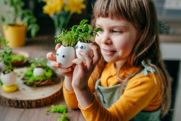 Wall Mural - Little girl decorating eggshell with toy eyes on the table