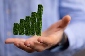 Businessman hand holding step of coins stacks with tree growing on top in nature green background. Money saving, investment