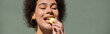 pleased african american woman eating yellow candy, banner