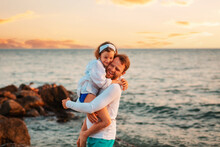 Father's Day. Portrait Of Embrasing Happy Father And Daughter Have A Funny Time. On The Background Sunset Sky And Ocean. Family Summer Vacations