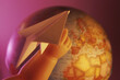 © SuperStock - Close-up of a doll's hand holding a paper plane near a globe