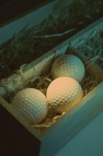Close-up Of Three Golf Balls In A Wooden Box