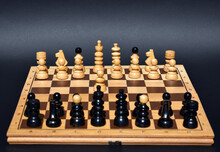 Wooden Chess Board With Chess Pieces On And Black Background.