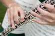 © SuperStock - Close-up of a musician's hands playing a clarinet with a sheet music in the background