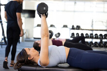 Young Woman In Gym Doing Chest Strengthening Exercise With Dumbbell