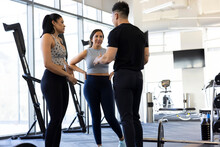 Trainer Explain Benefits Of A Workout To Two Women In Gym