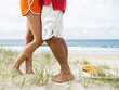 © SuperStock - Waist down image of man and woman embracing, standing in the sand at the beach