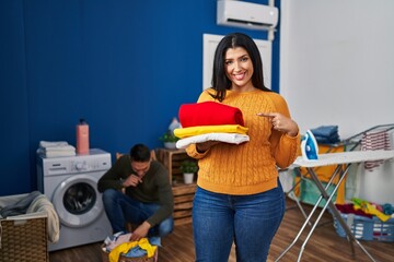 Poster - Young couple doing laundry at home smiling happy pointing with hand and finger