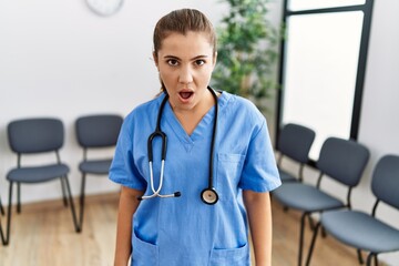 Poster - Young brunette doctor woman at waiting room scared and amazed with open mouth for surprise, disbelief face