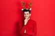 © Krakenimages.com - Young hispanic man wearing cute christmas reindeer horns with hand on chin thinking about question, pensive expression. smiling with thoughtful face. doubt concept.