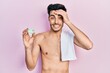 © Krakenimages.com - Young hispanic man shirtless wearing towel and eye bags patches stressed and frustrated with hand on head, surprised and angry face