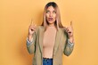 © Krakenimages.com - Beautiful hispanic woman wearing business jacket amazed and surprised looking up and pointing with fingers and raised arms.