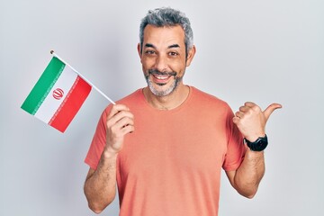 Sticker - Handsome middle age man with grey hair holding iran flag pointing thumb up to the side smiling happy with open mouth