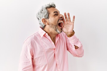 Canvas Print - Middle age hispanic man standing over isolated background shouting and screaming loud to side with hand on mouth. communication concept.